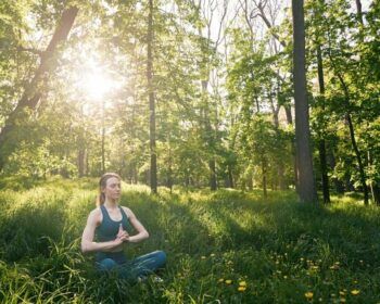 Woman meditating in the forest under sunlight